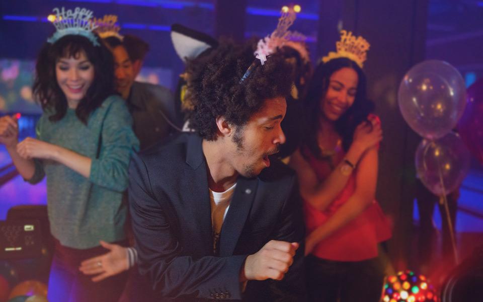 Group of people dancing with happy birthday tiaras