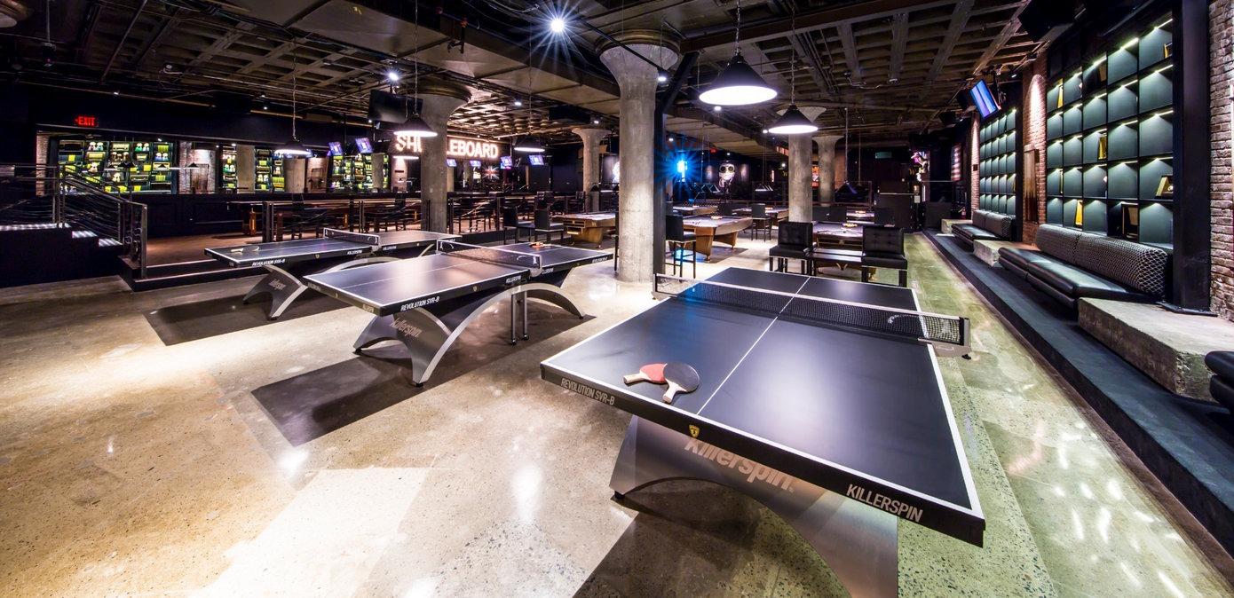 Several ping pong tables in a large bar area