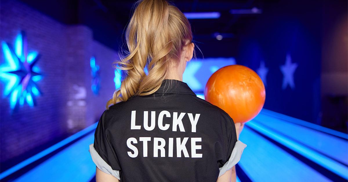 Bowler holding bowling ball and preparing to bowl with a Lucky Strike bowling shirt