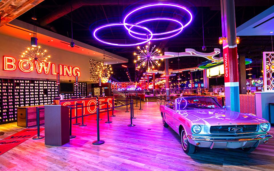 Pink mustang with colorful lights and bowling center in background