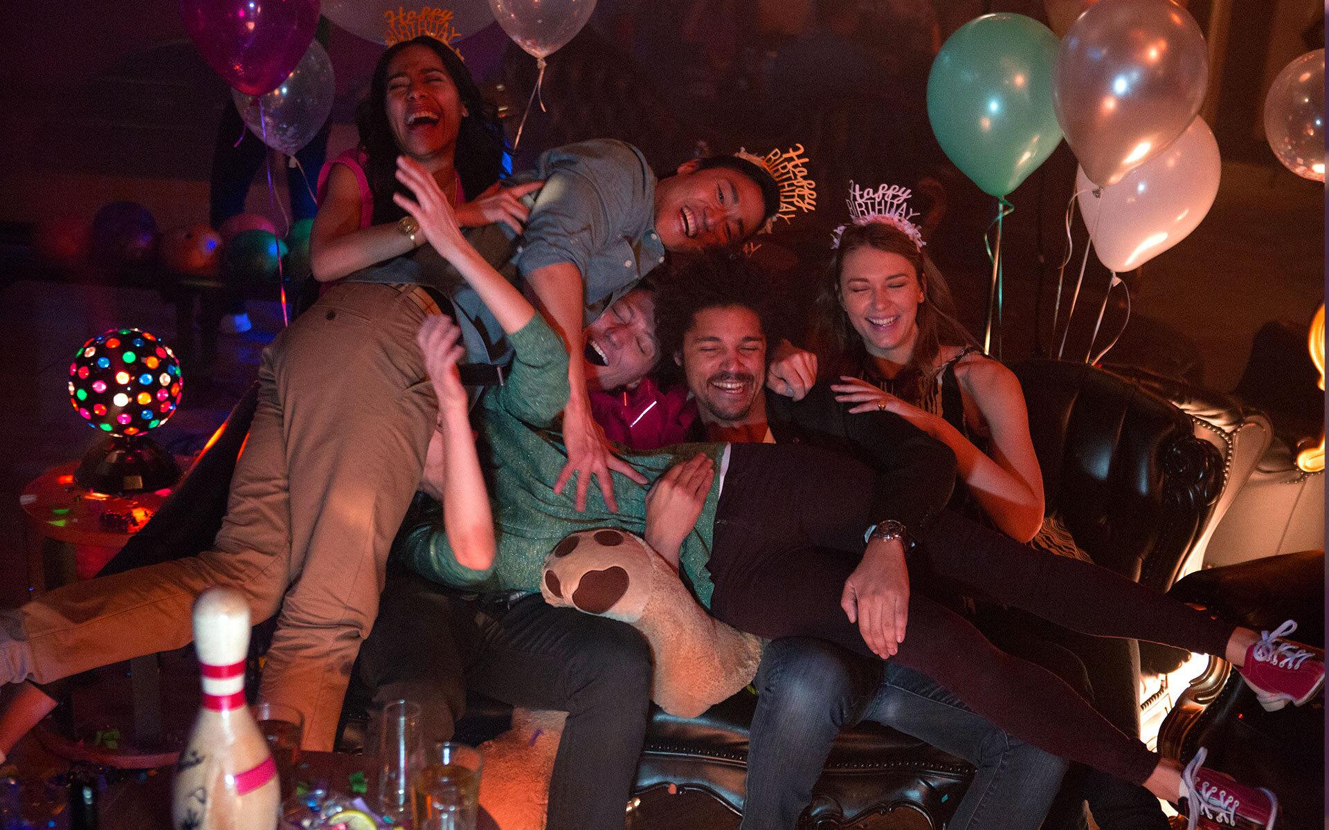 A group of friends having fun with balloons and party hats.