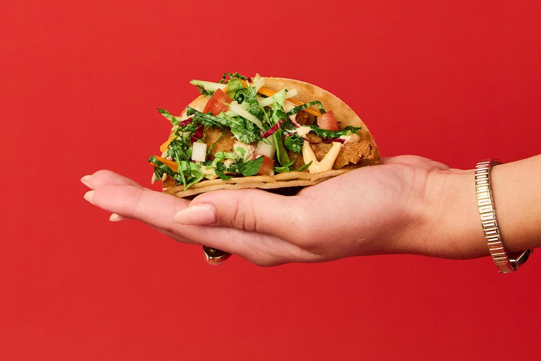 A girls hands holding a cauliflower taco. 