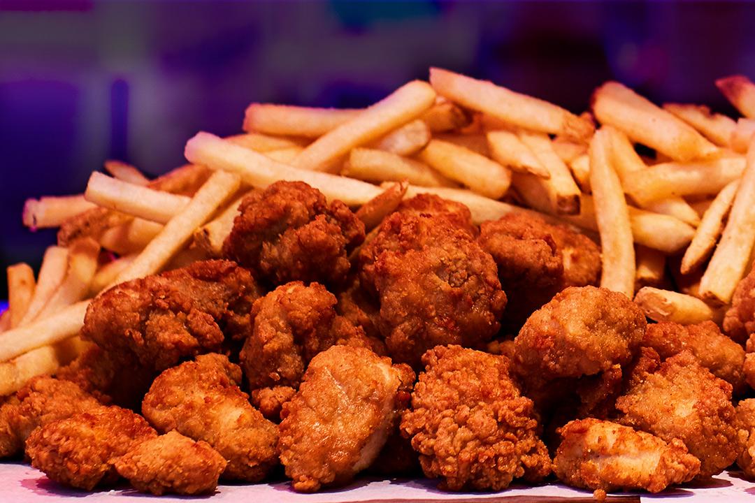 A pile of boneless wings with french fries. 