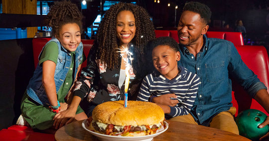family sitting around a six-pound behemoth burger lit with sparklers